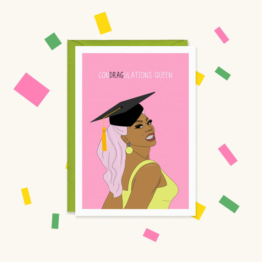 Greeting card of RuPaul with pink hair wearing a graduation cap on a pink background, reading "Condragulations Queen"