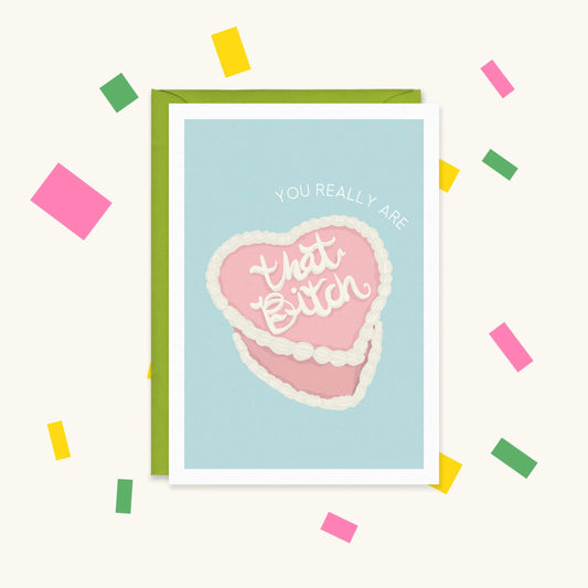 Greeting card with a pink heart-shaped vintage cake piped with "that Bitch" under "YOU REALLY ARE" on pale blue