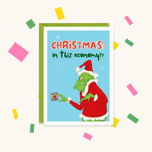 Greeting card of the Grinch in a Santa suit pressing a 'Will destroy economy' button, text 'Christmas? In this economy?!'