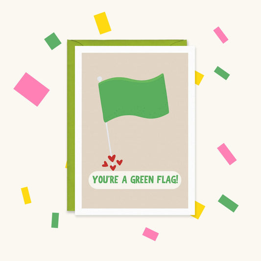 Greeting card with a green flag on a pole and little red hearts at its base, reading "You're a green flag!"