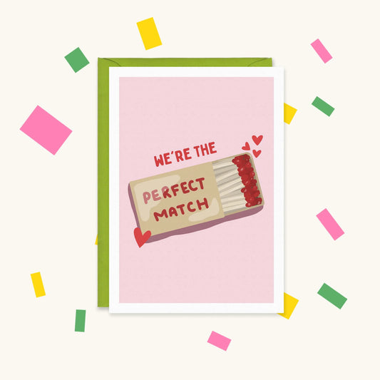 Greeting card with an open matchbox of red-tipped matches and hearts on pink, reading "We're the perfect match"