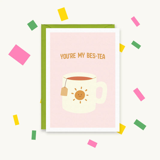 Greeting card with a cream mug of tea with a teabag and a smiling sun on pink, reading "You're my bes-tea"