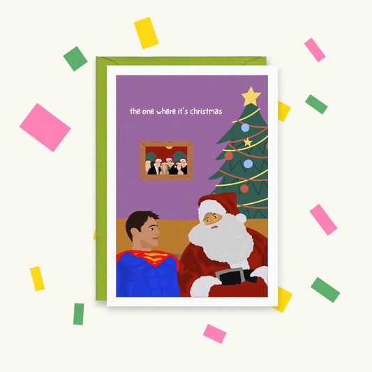 Greeting card of Joey in a Superman costume beside Santa by a Christmas tree, text 'the one where it's christmas'