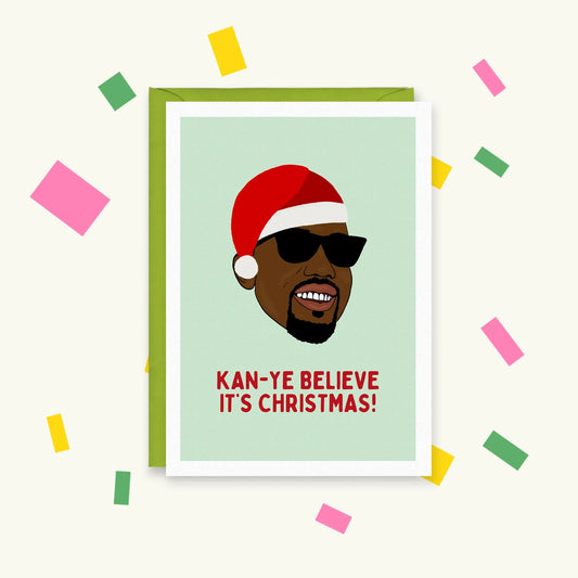 Greeting card with illustrated Kanye West in a Santa hat and sunglasses, text 'Kan-ye believe it's Christmas!'