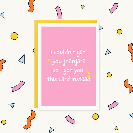 Greeting card, pink with white handwritten text and yellow sparkles: "i couldn't get you jhanjara so I got you this card instead"